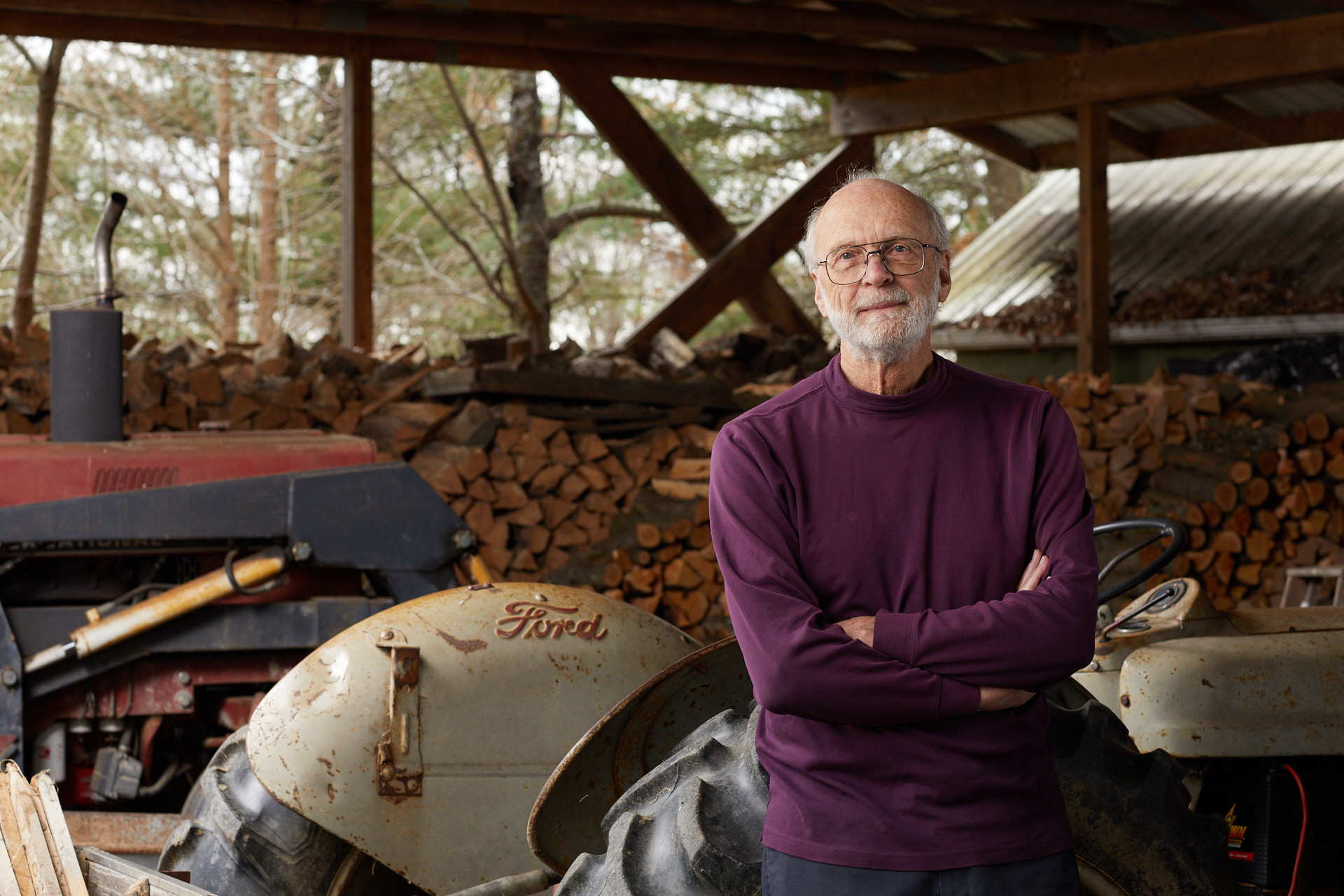 An editorial photo of a man leaning against an old tractor by editorial photographer Tracey Brown